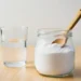 Bicarbonate de soude dans un bocal en verre avec une cuillère en bois et un verre d'eau